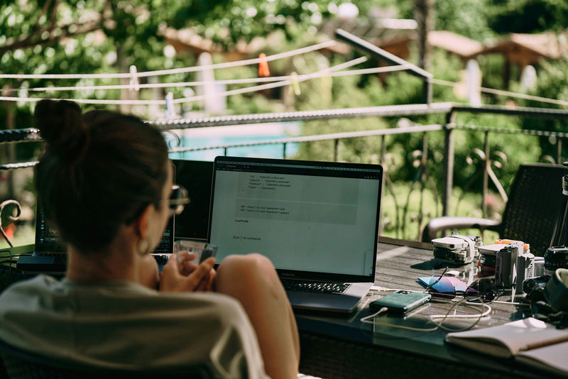 Digital nomad English teacher working on a laptop at an outdoor table while traveling abroad