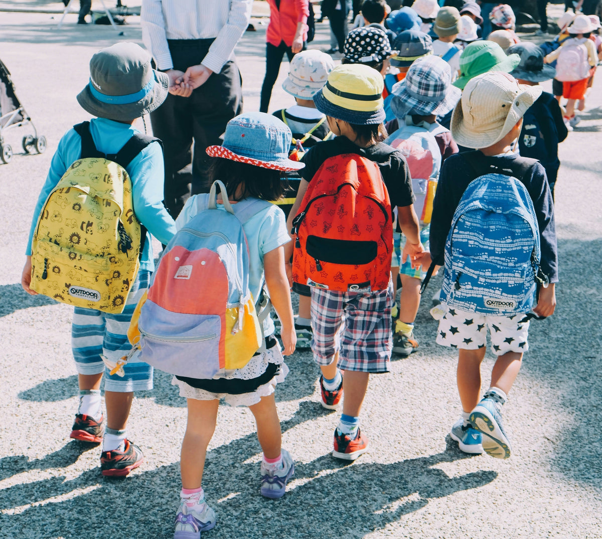 Japanese school children in colorful hats and backpacks walking to class, a daily sight for English teachers in Japan