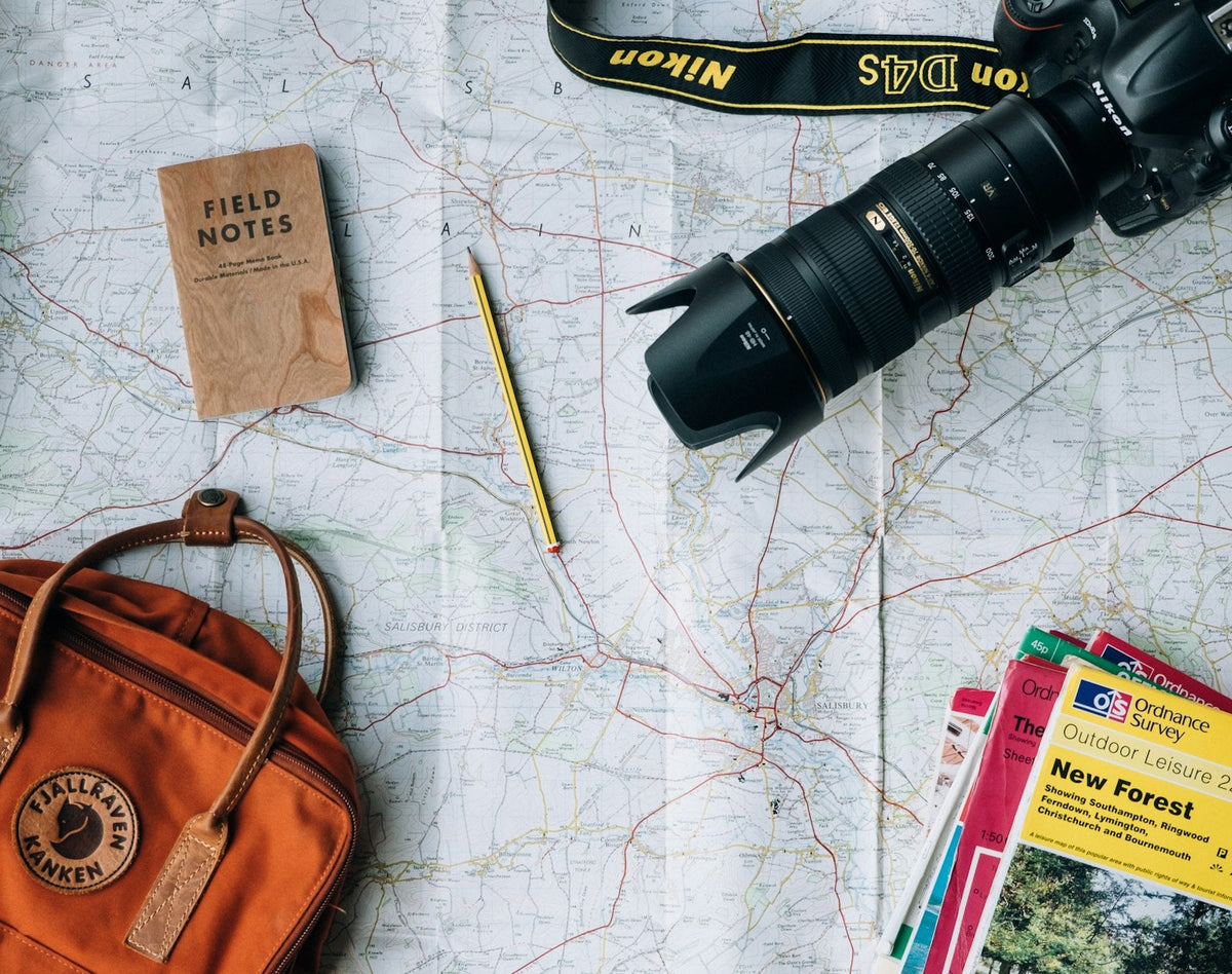 Backpack, map, and camera laid out while planning a gap year teaching English abroad