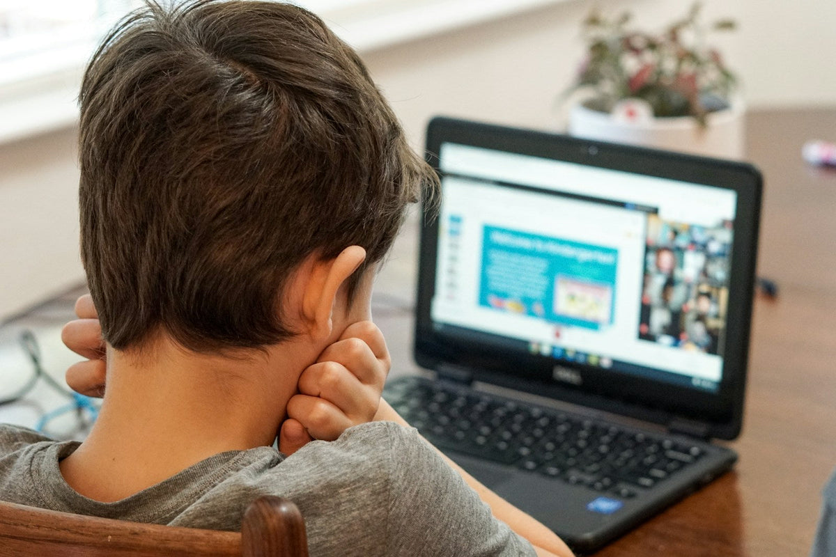 Student studying a TEFL course online with a laptop and notebook, comparing cheap TEFL courses