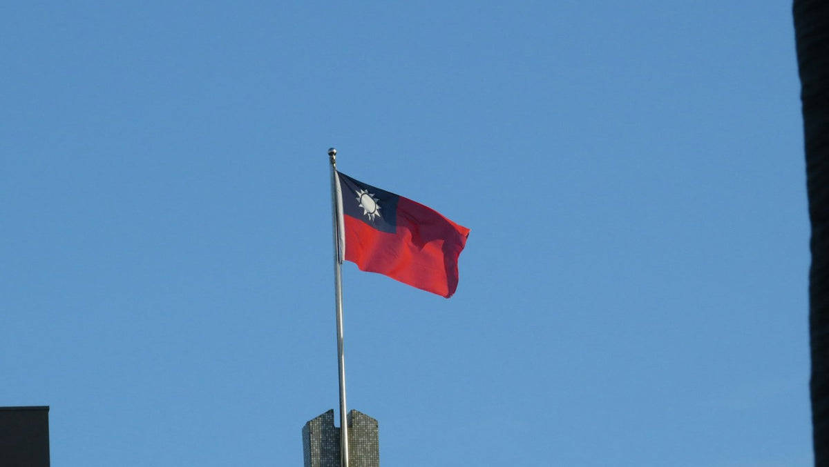 Taiwanese flag waving against a blue sky, illustrating work visa and ARC rules for English teachers in Taiwan