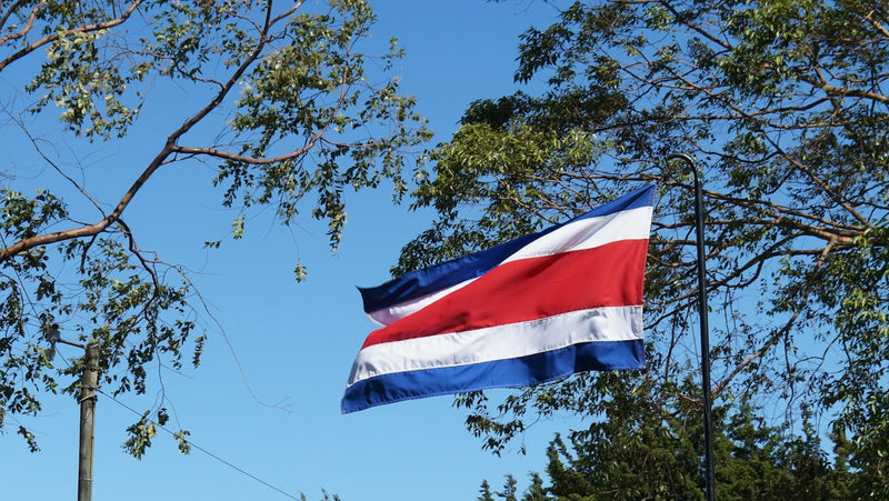 Costa Rican flag against a blue sky, illustrating work visa rules for English teachers in Costa Rica