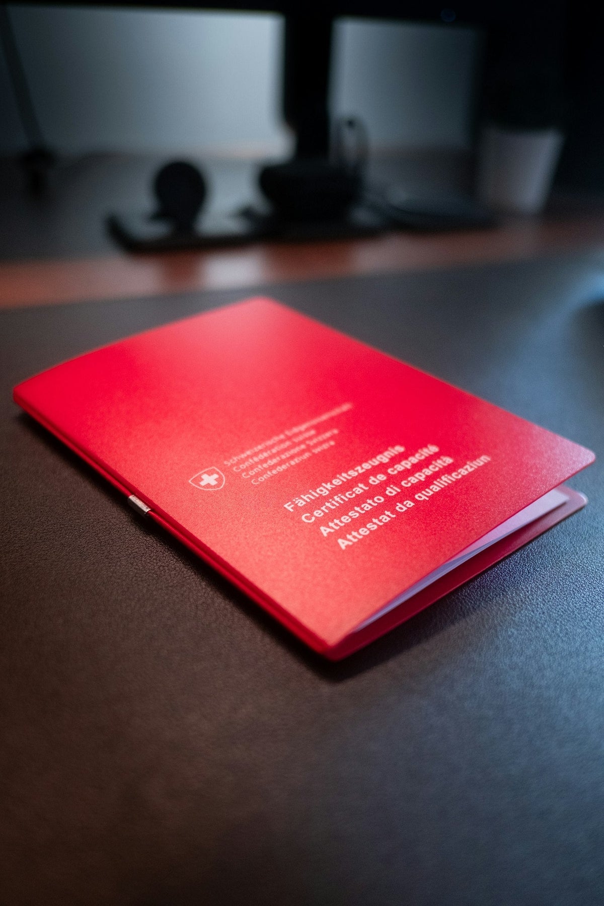 Red TEFL style certificate of qualification resting on a dark desk