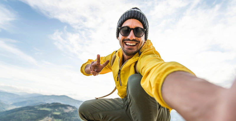 Smiling traveller in a yellow jacket taking a selfie