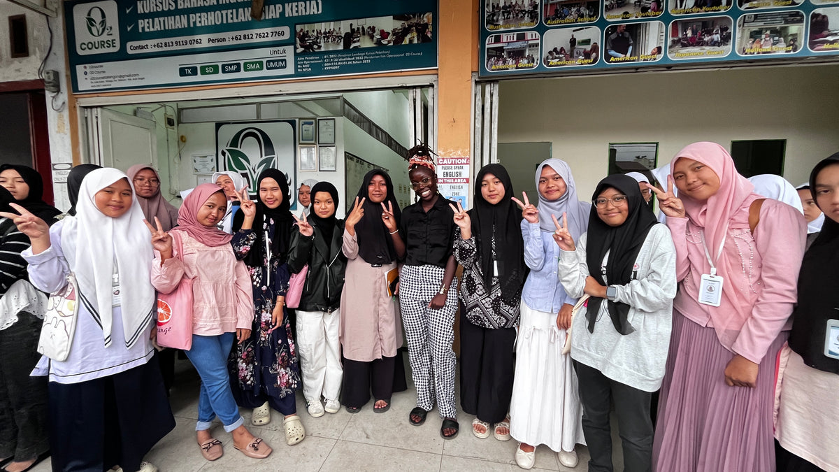 Group of women in various outfits posing for a photo in a public setting. Vicky
